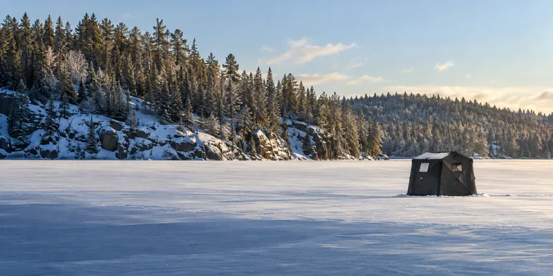 Portable fishing shelter on a snow-covered lake beneath a winter sky